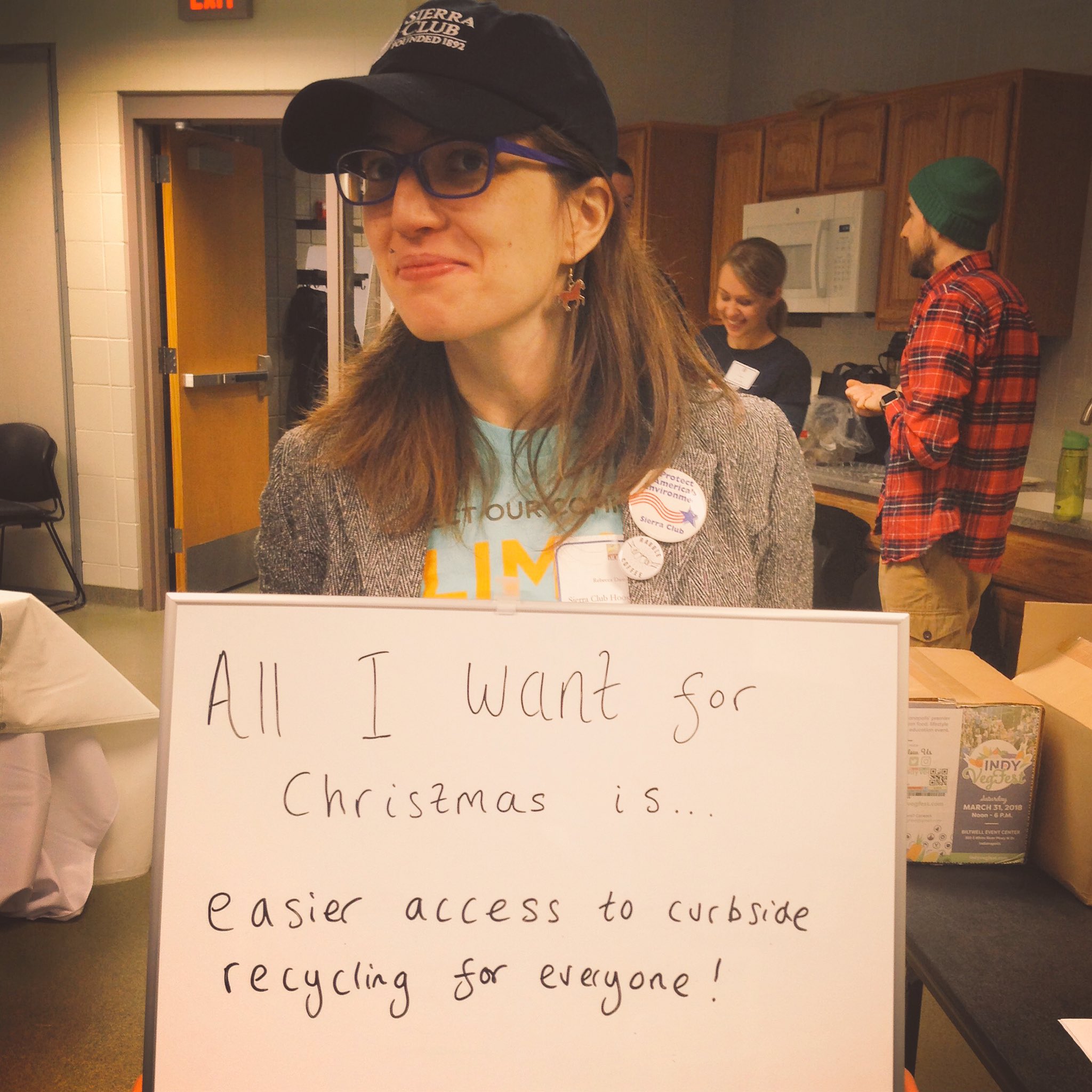 Rebecca from the Hoosier Chapter holds a sign saying "all I want for Christmas is easier access to curbside recycling for everyone"