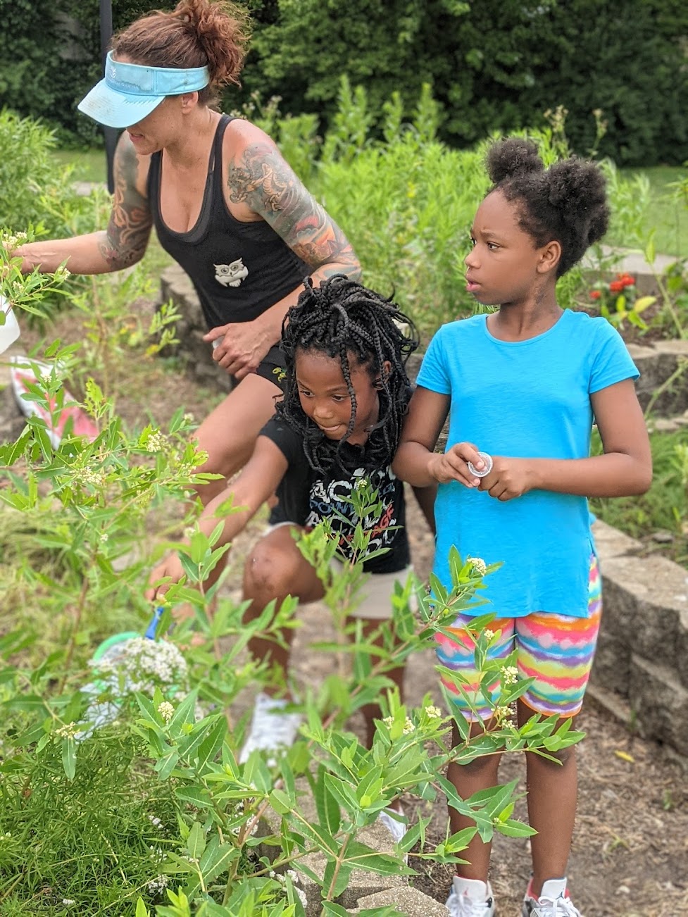 Two young children and a Sierra Club staff member explore a Monarch butterfly garden.