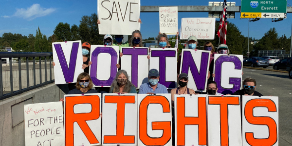 A group of volunteers holding up signs that spell out "Save Voting Rights!"