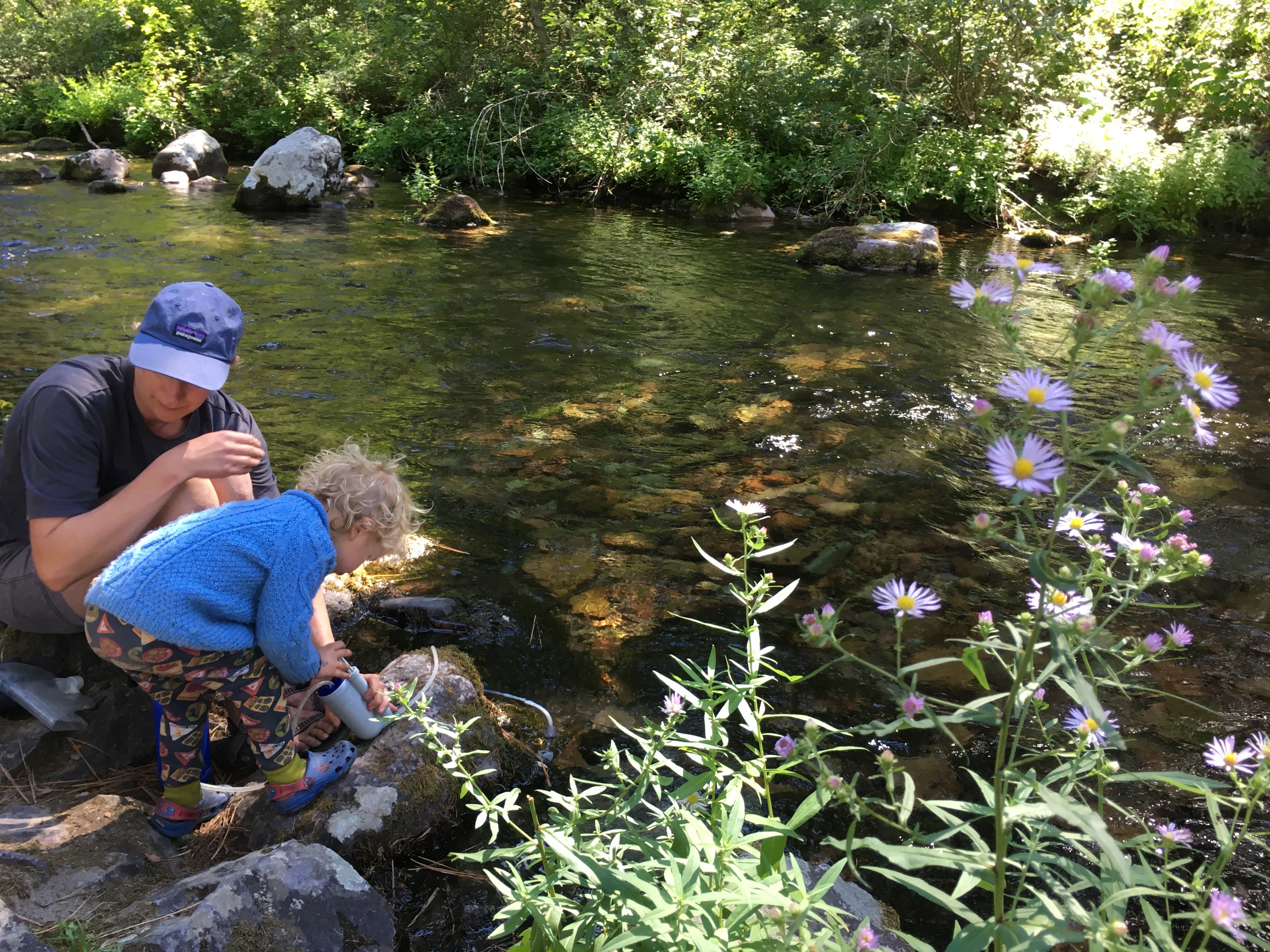 A mother helps her small child using water filter pump.