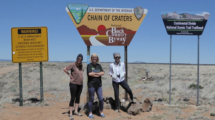 People standing in front of Chain of Craters Road sign