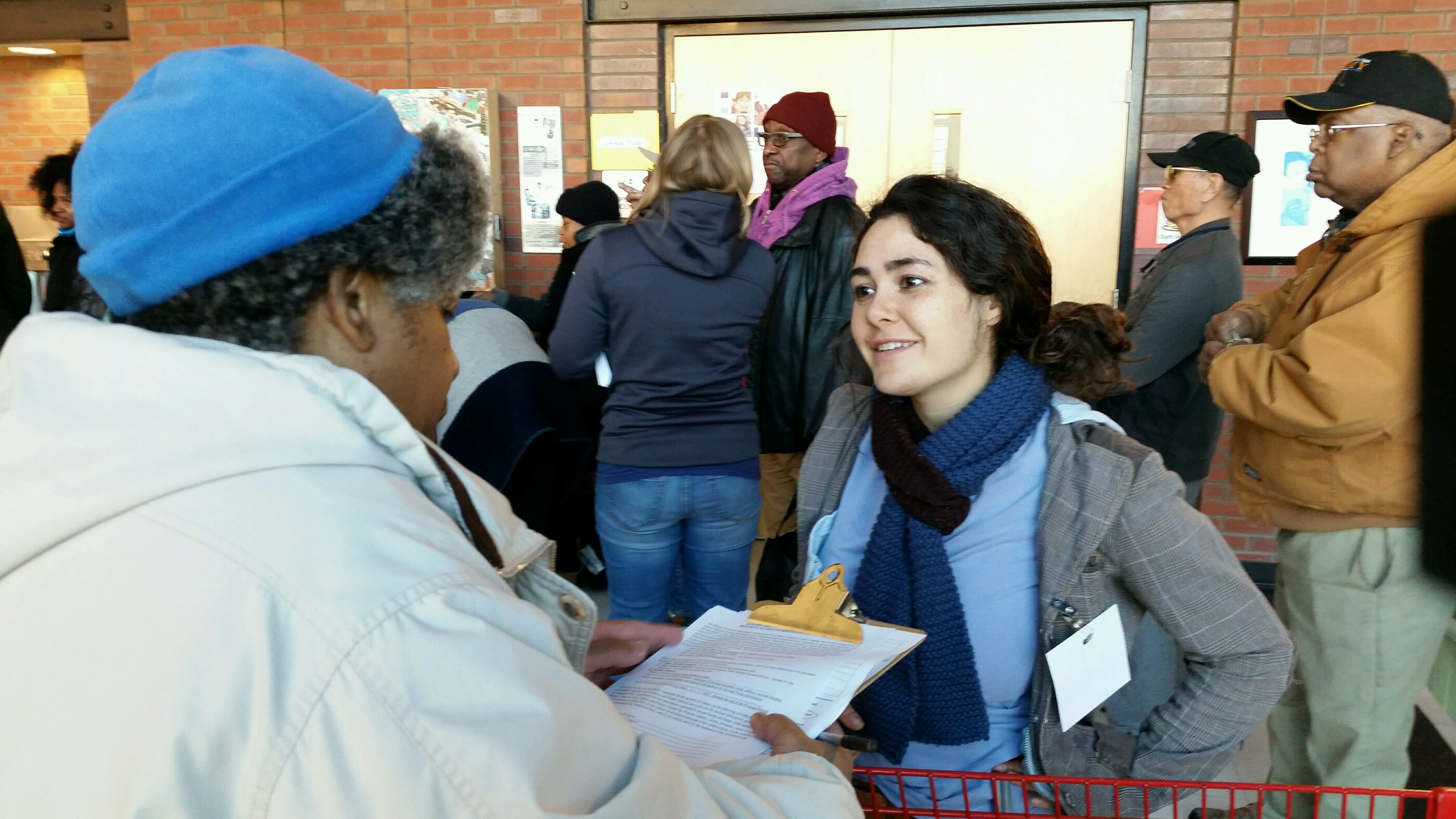 Sierra Club Ready for 100 Organizer Eva Resnick-Day is gesturing to Homewood resident as she signs up for Grassroots Green Homes program clipboard in hand at the Community Food Bank