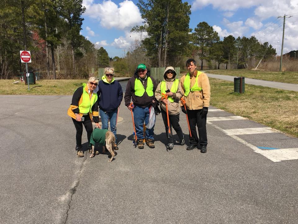 Image depicts five volunteers wearing jackets and bright yellow safety vests