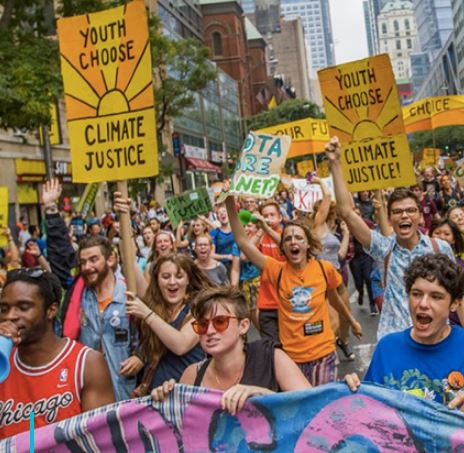 A group of young people at a march hold up signs that read "Youth Choose Climate Justice"