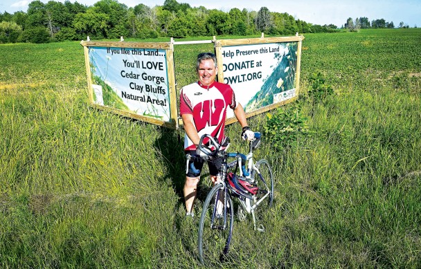 Andrew Struck on bicycle at Cedar Gorge sign