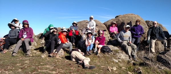 Hardy hikers relax atop Monument Peak on a windy day.                         