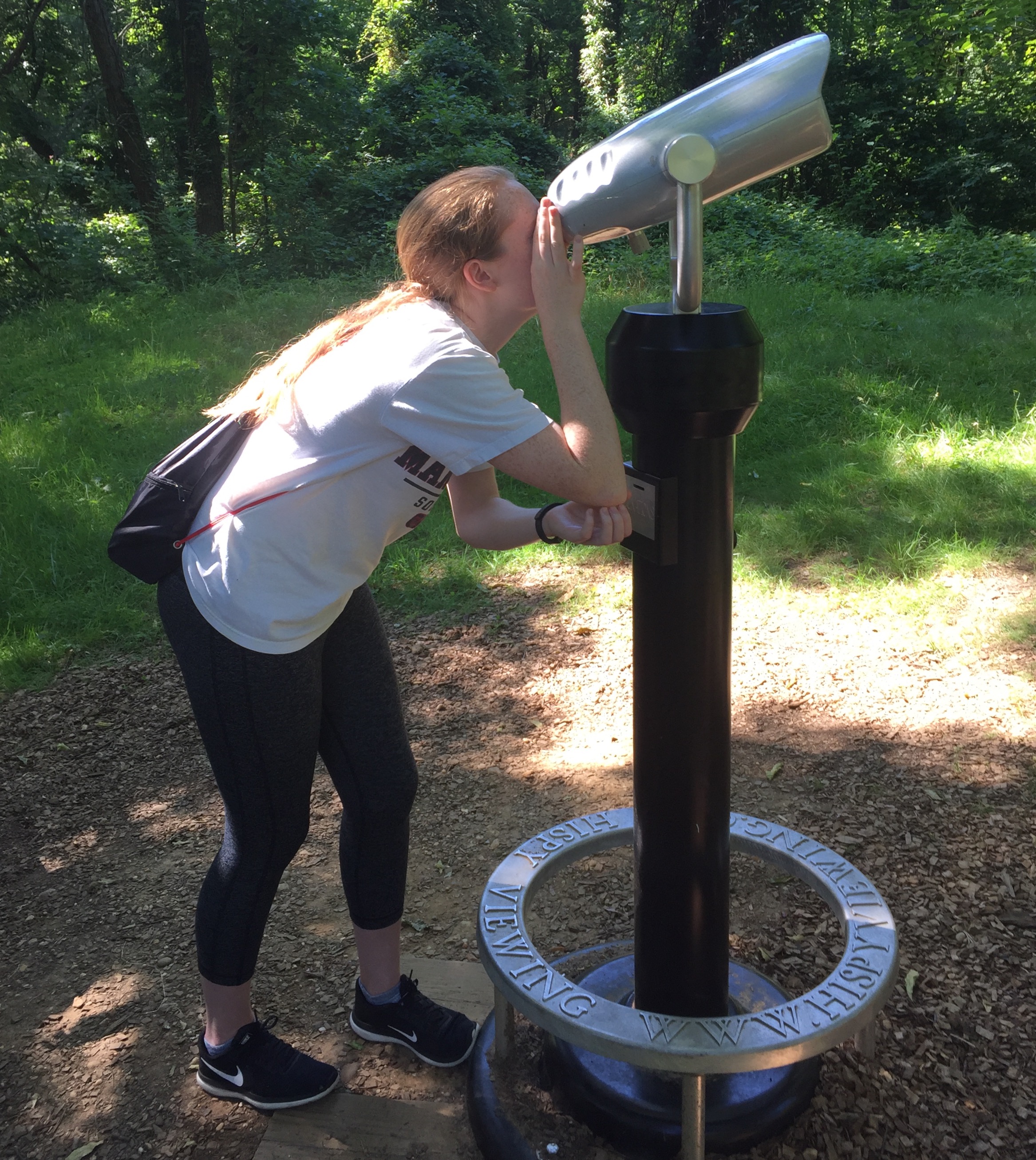 Hiker peers through a telescope at a bald eagles nest