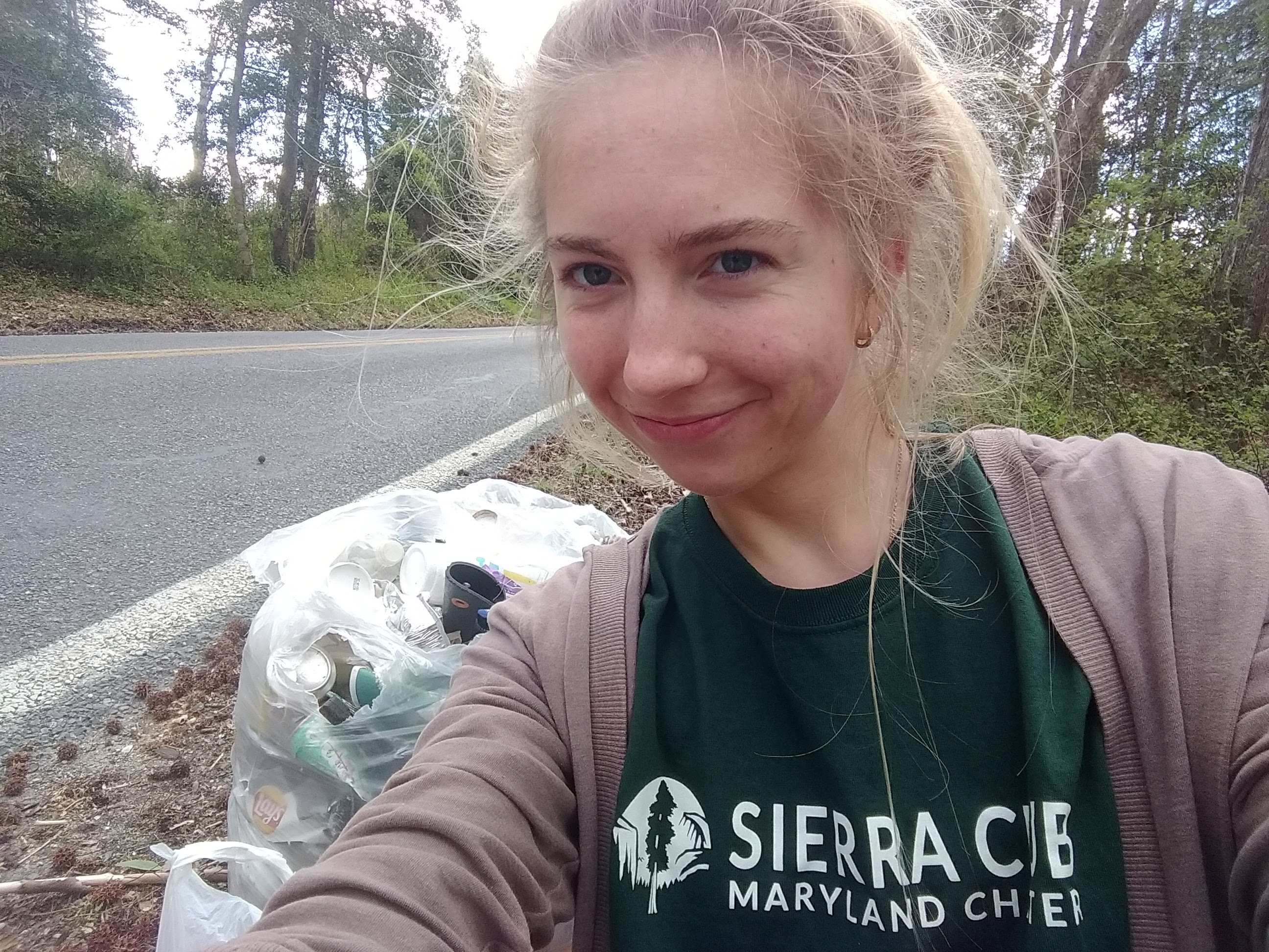 Sierra Club volunteer in college picks up trash by road