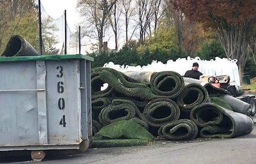 Pile of rolled turf next to dumpster