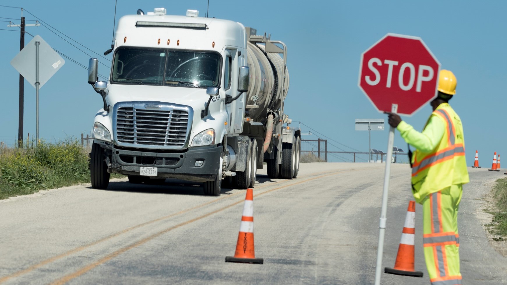 tractor trailer truck, person holding stop sign to let pass