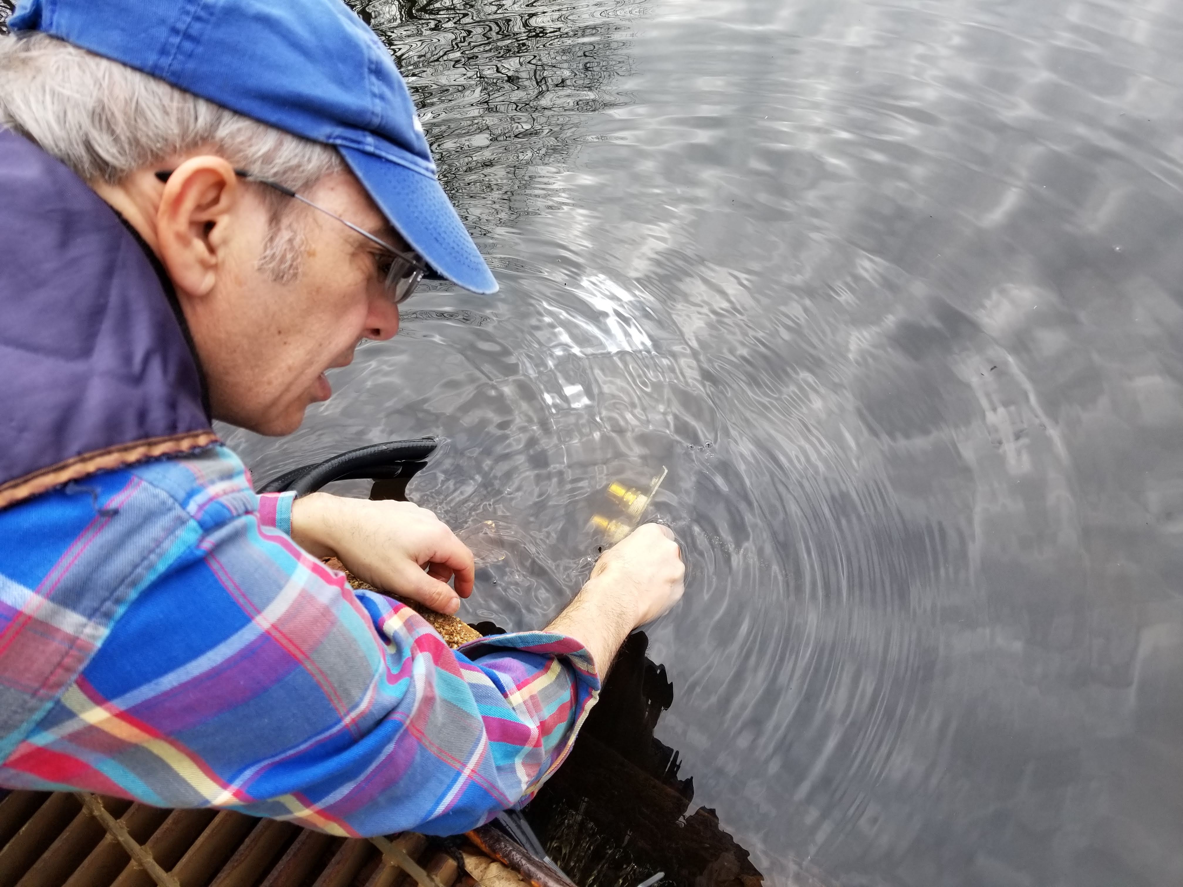 Volunteer Mike Richardi holding the water intake above the dam