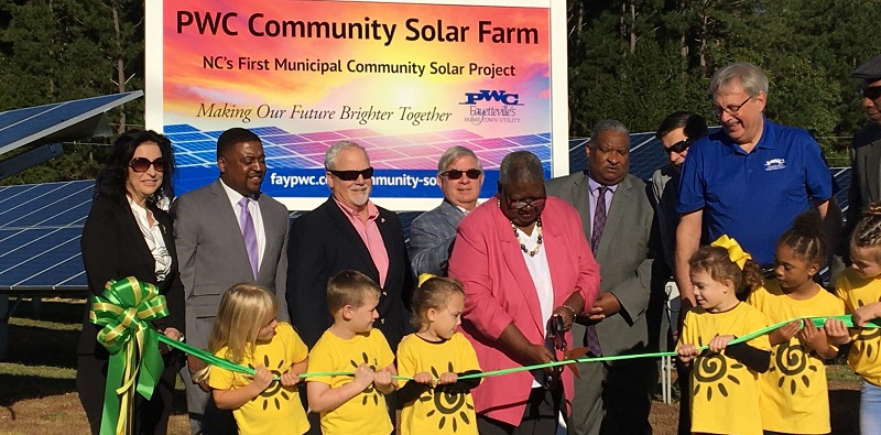 A group of adults and children cut a ribbon for the new Fayetteville Community Solar project