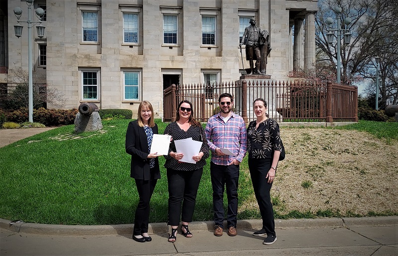 Representatives of SELC, NC Sierra Club and CleanAIRE NC hold pages of a petition outside the NC State Capitol building in Raleigh