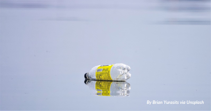 An empty, discarded plastic bottle floats on a calm body of water