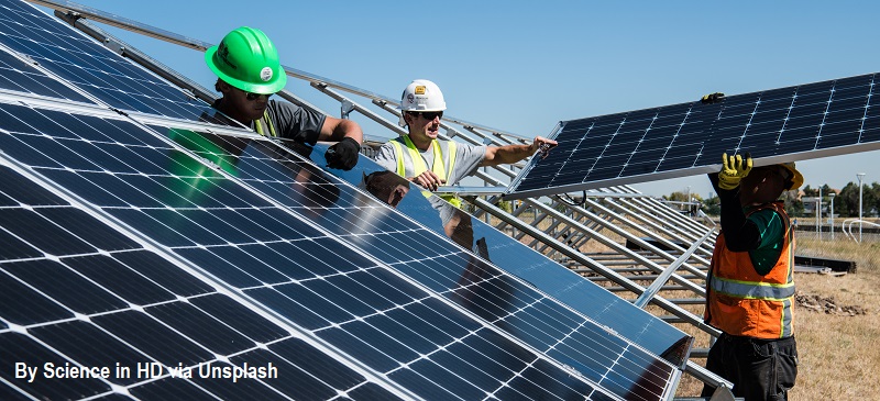 Three men in hard hats install solar panels