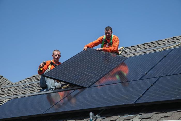 Energy Bill photo of workers installing solar panels on a roof