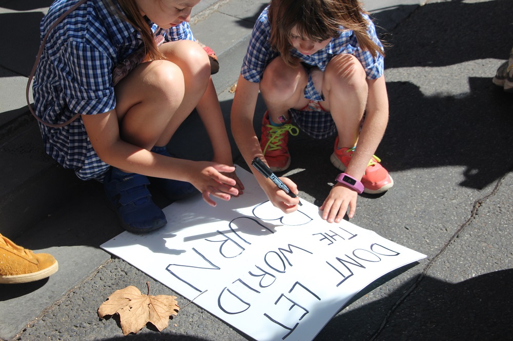 Photo of two girls making a 'Don't Let the World Burn' poster
