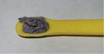 photo of material recovered from washing one fleece jacket, on a yellow plastic scoop