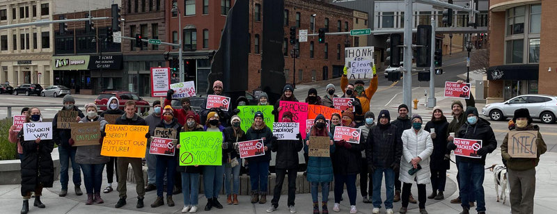 photo of people holding signs protesting against the NTEC gas plant