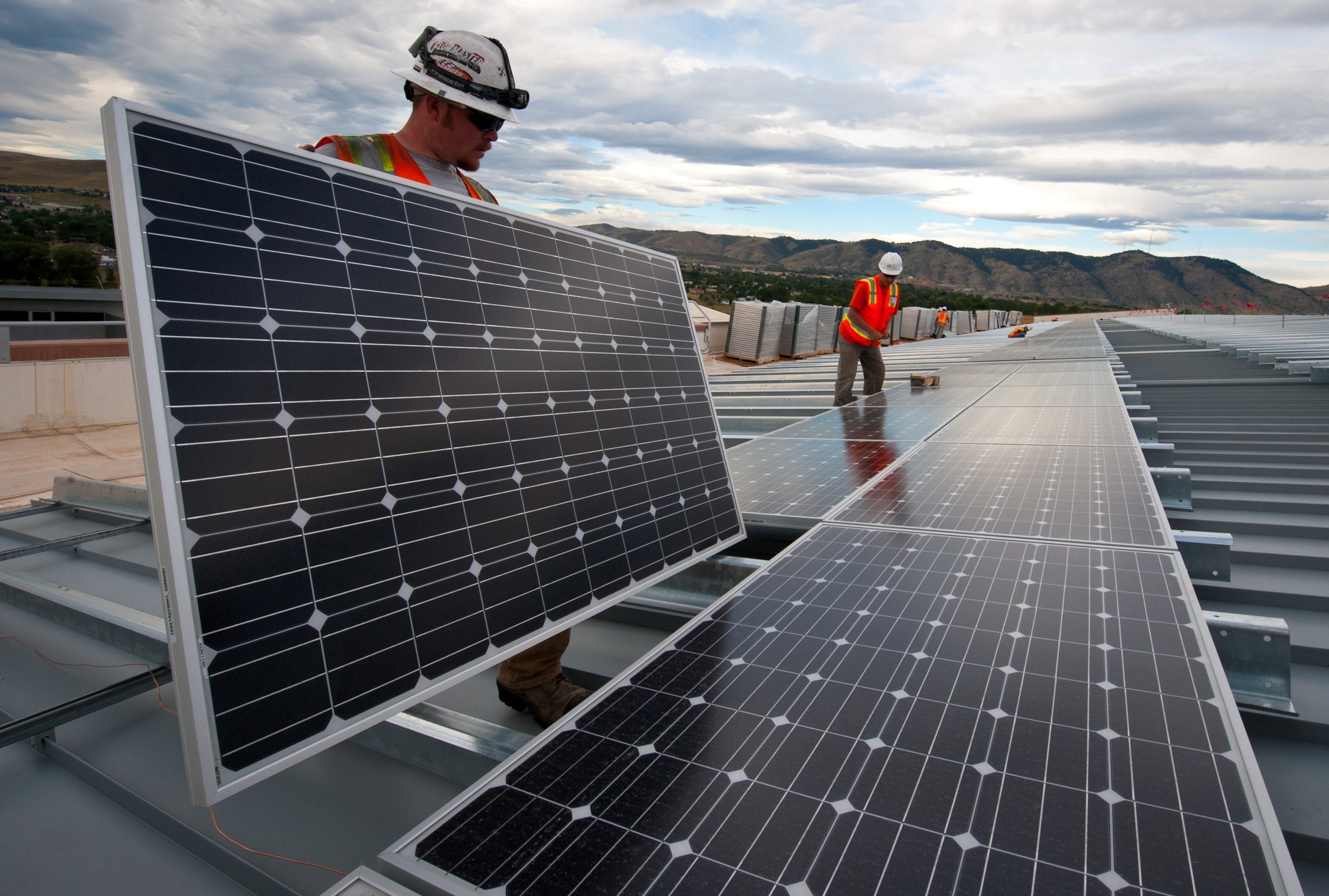 Workers putting solar panels on building 