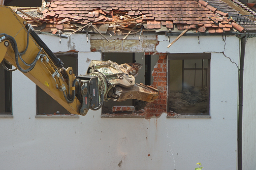 Yellow excavator arm is reaching into empty building window