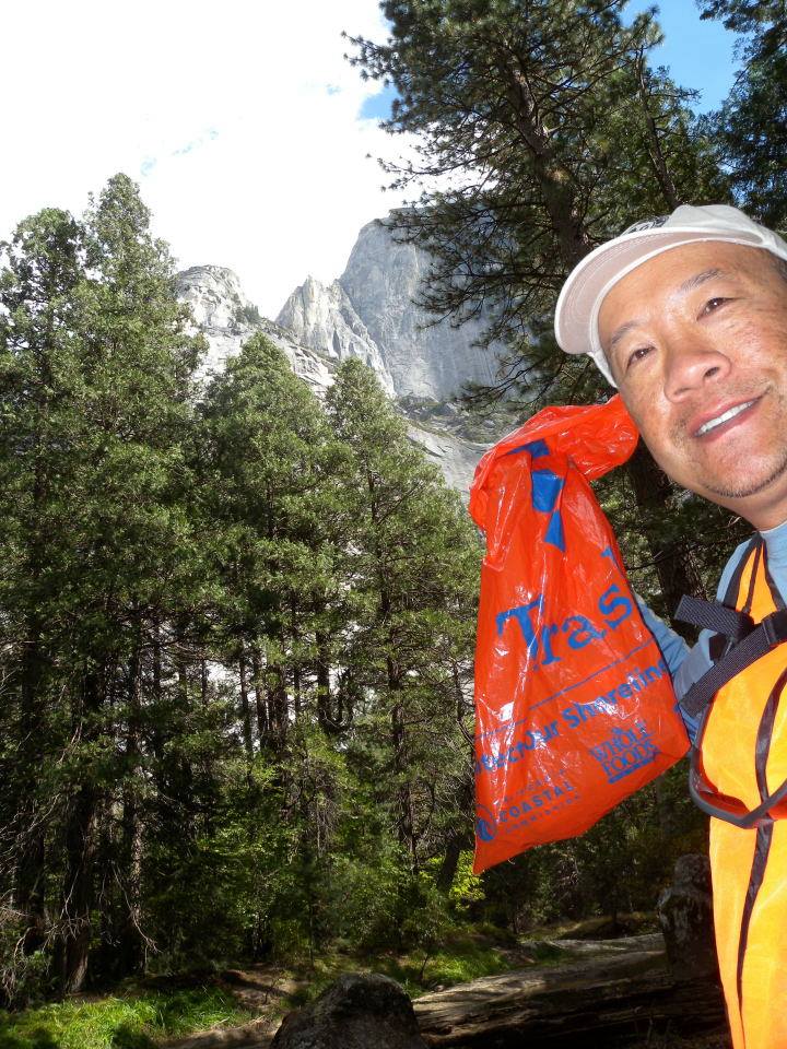 Smiling man with a bag of garbage posing with Half Dom in the background