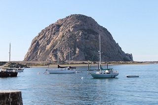 Moored sailboats in the foreground and Morro Rock behind on a clear day