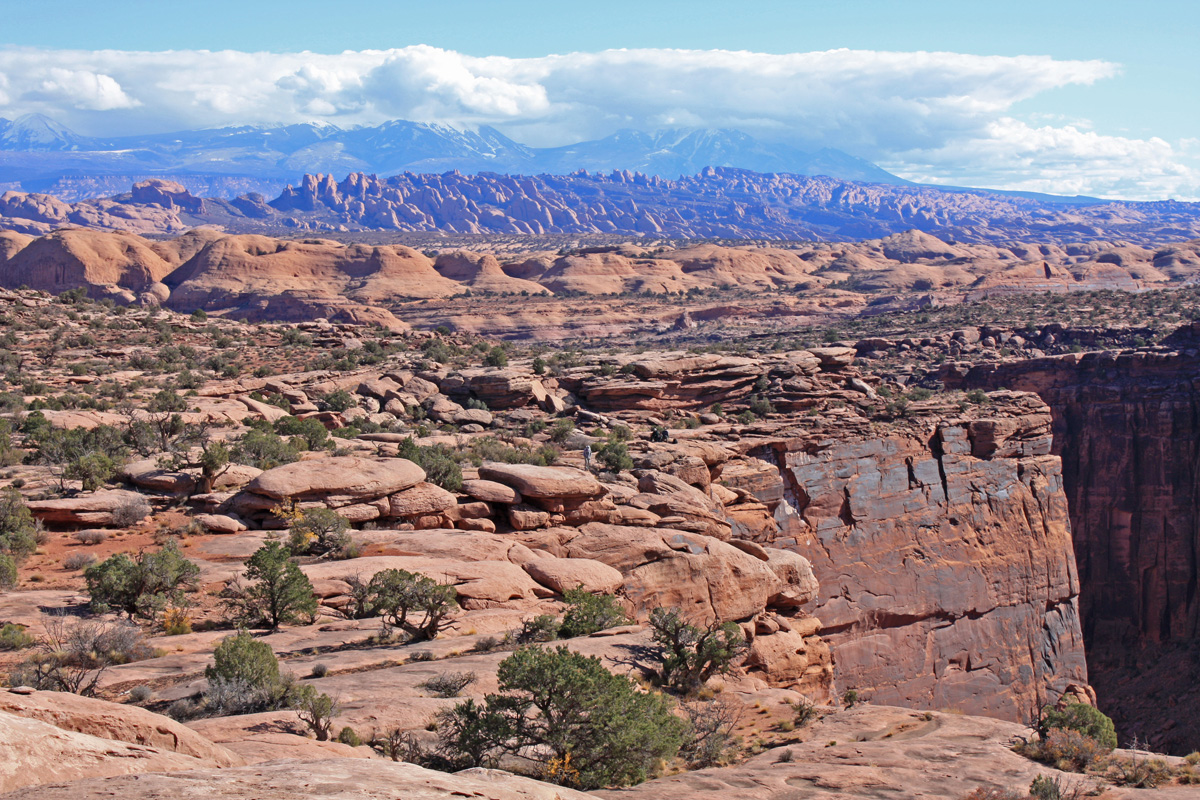 Clouds and mountains in the background with red rock formations in the foreground