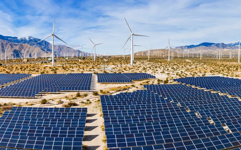 A field of solar panels and windmills in the desert.