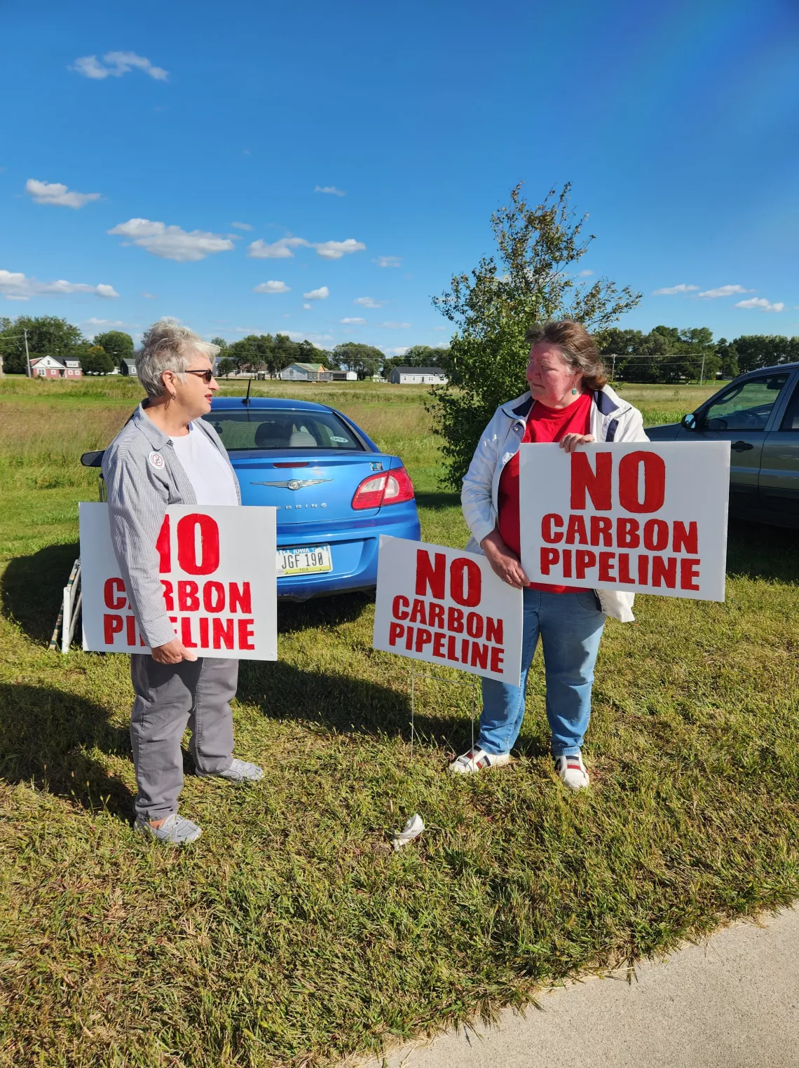 2 people with signs saying "NO Carbon Pipeline"