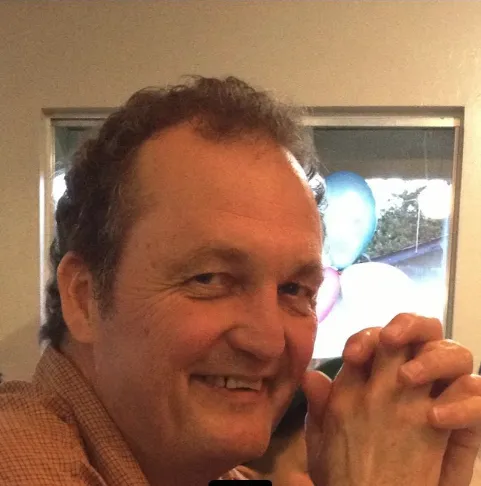 Mark Linde smiles in front of a window
