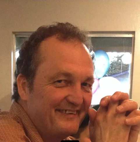 Mark Linde smiles in front of a window