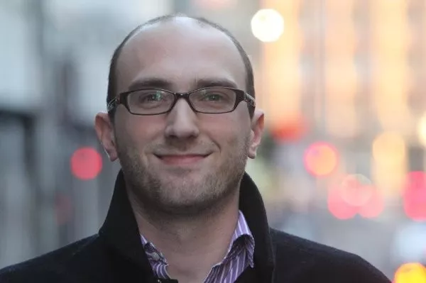 Kieran Farr smiles on a blurred city background