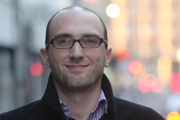 Kieran Farr smiles on a blurred city background