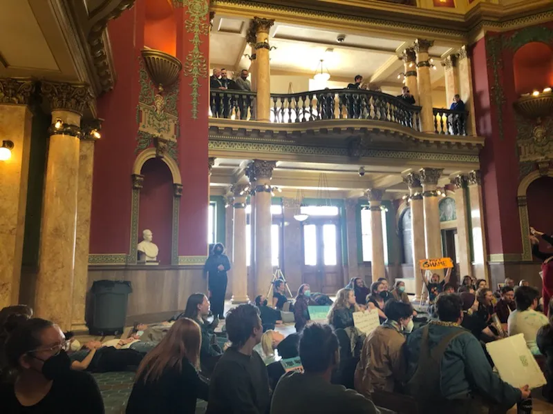Interior view of the Montana State Capitol with a large number of people sitting on the floor