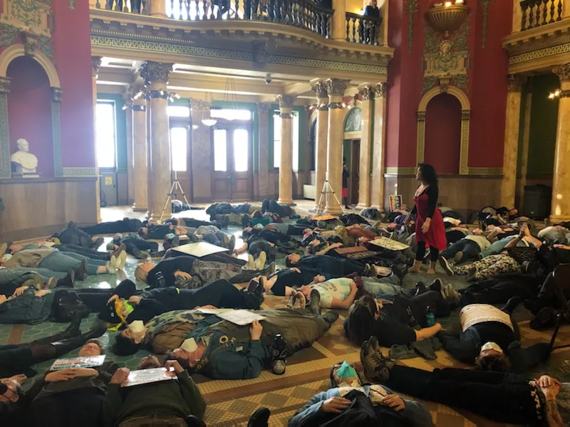 Interior view of the Montana State Capitol with a large number of people lying down on the floor