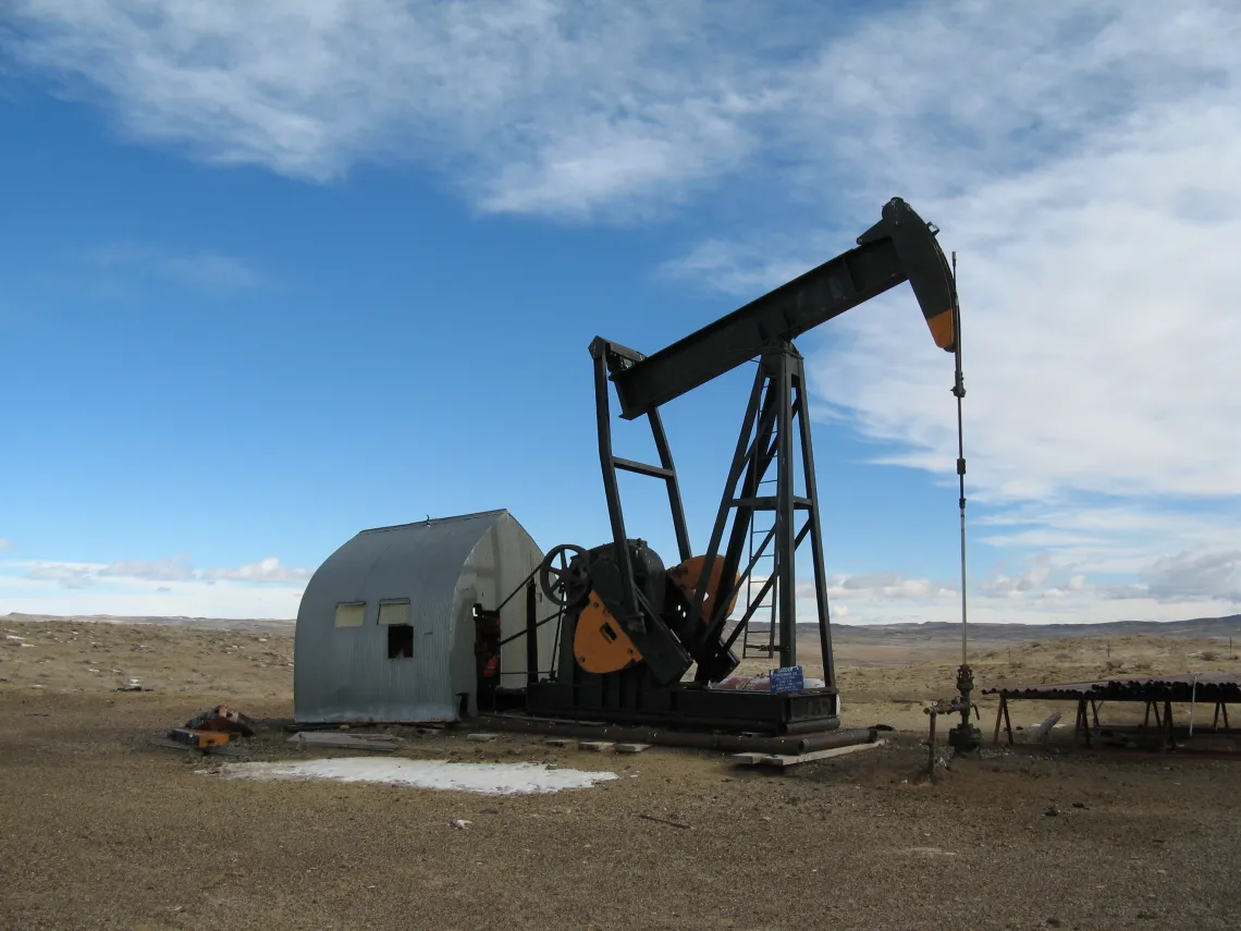An oil well operating in an open field under a blue sky 