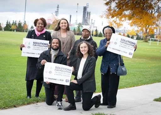 Background of Detroit with Climate Justice leaders posing with signs