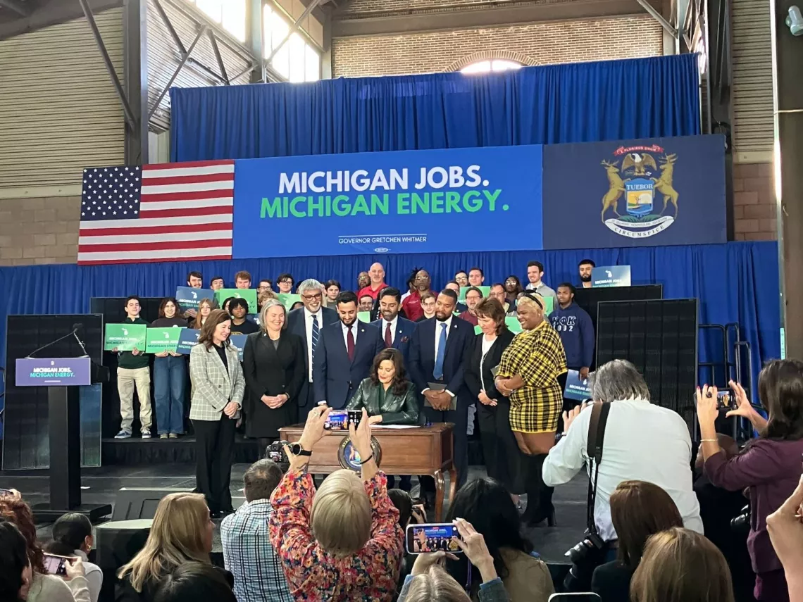 Photo of Governor Whitmer signing clean energy bills with crowd behind