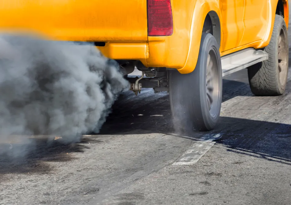 An orange pickup truck spews dark, gray exhaust.