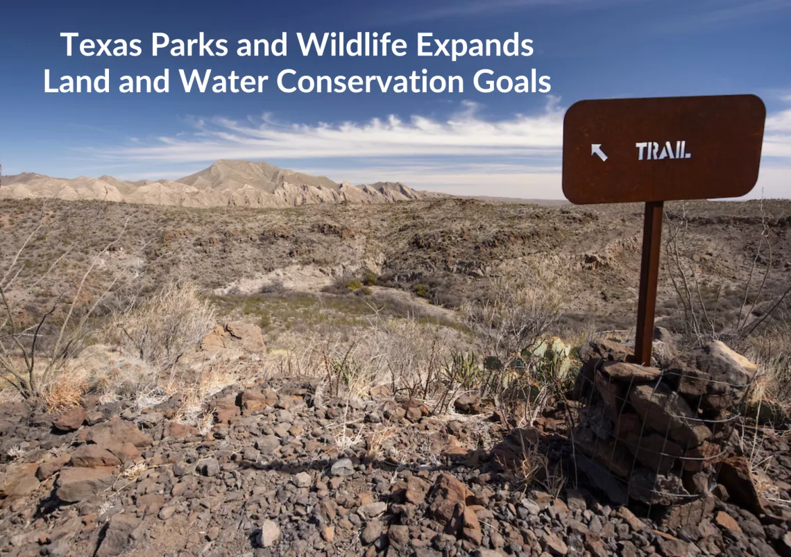 Up on a scraggly ridge a metal sign reads "TRAIL" with an arrow pointing upward and to the left. Text: Texas Parks and Wildlife Expands Land and Water Conservation Goals