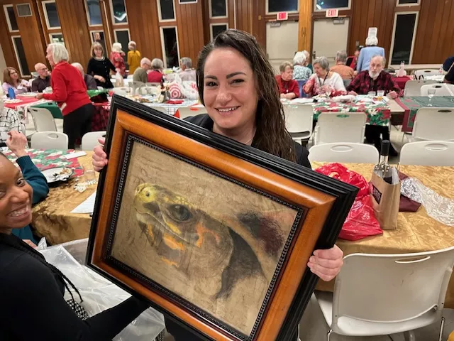 Maria Chilbert holds turtle art she bid on