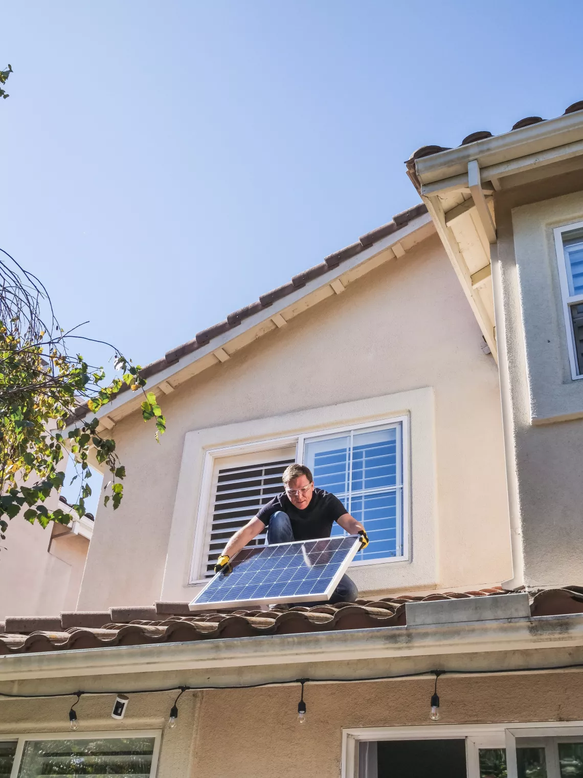 man holding solar panel on house roof