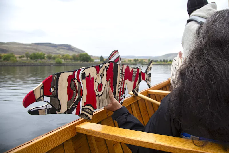 A wooden piece of art in the shape of a salmon and painted in bright colors