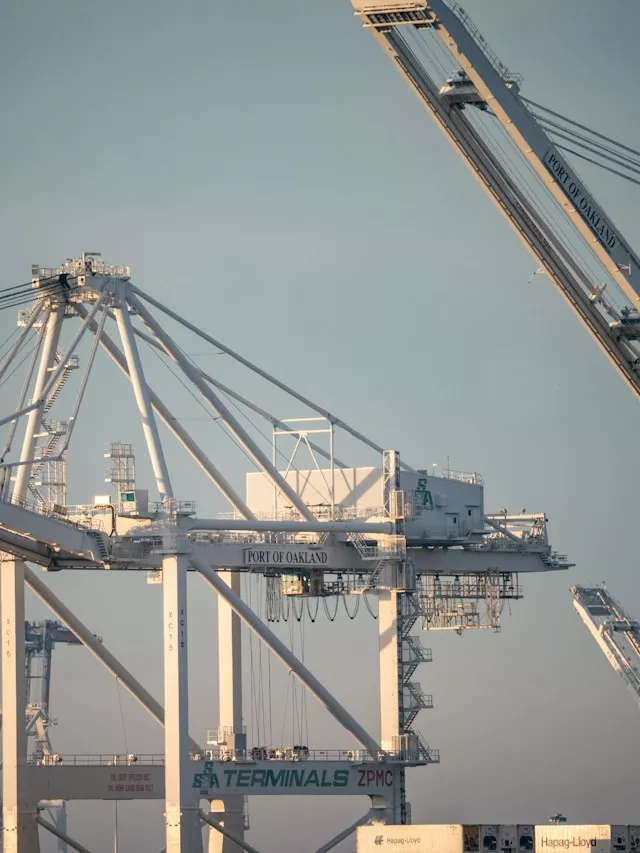 Port of Oakland cranes against pale blue sky