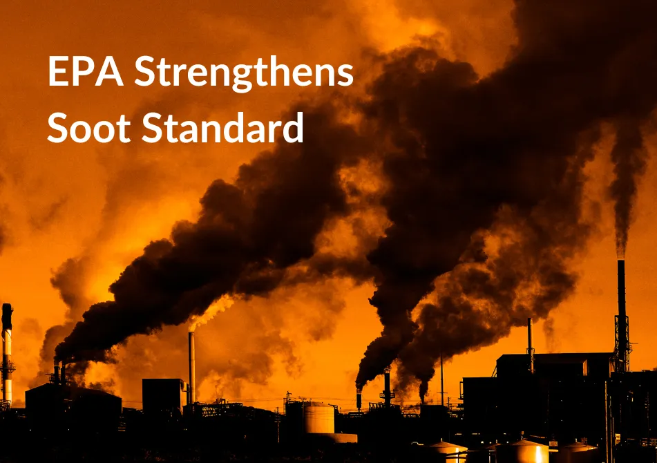 Several smokestacks spew plumes of dark pollution against the backdrop of a red sky.