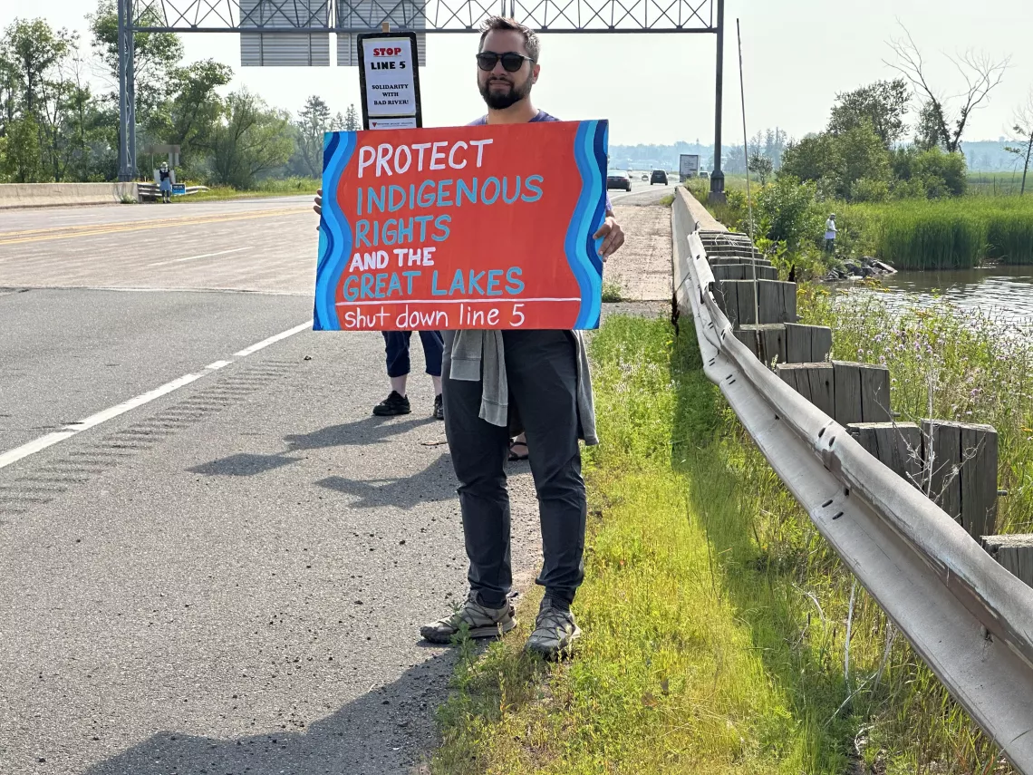 Community members stand along the roadside in Wisconsin to raise awareness of harms of Line 5 pipeline. (August 2023)