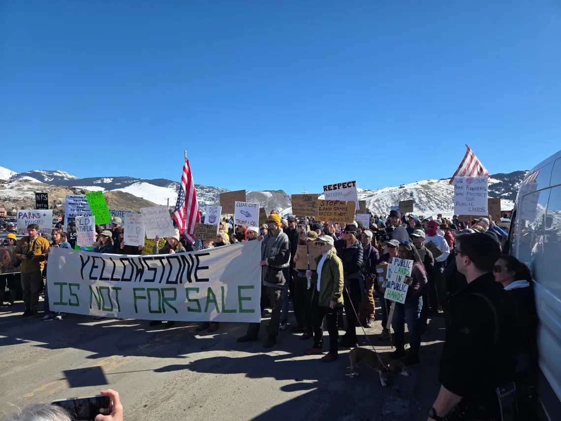 a group of people posing with signs including a large banner
