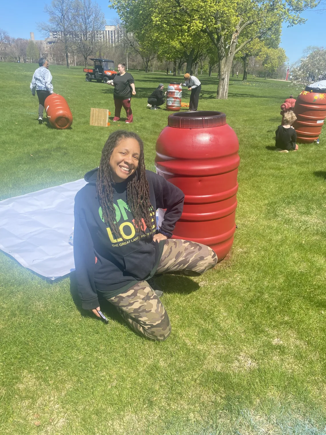 Organizer Mama Erin P Johnson poses in front of a rain barrel in Gabriel Richard Park