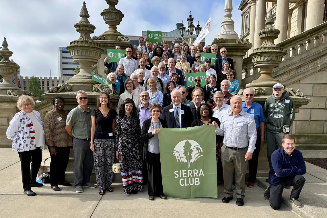 A group of volunteer lobbyists and Sierra Club staff gathered on the Michigan State Capitol steps with a Sierra Club banner and signs.